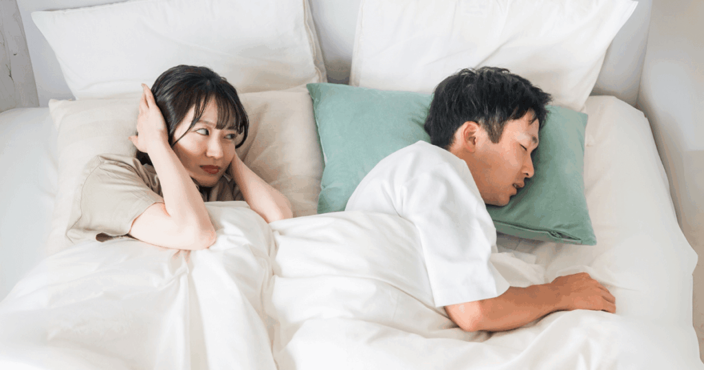 睡眠中の歯ぎしりに悩む女性と眠る男性